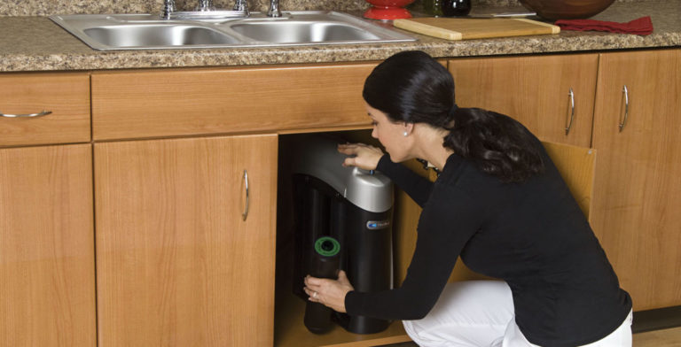 woman replacing cartridge in under sink water filter